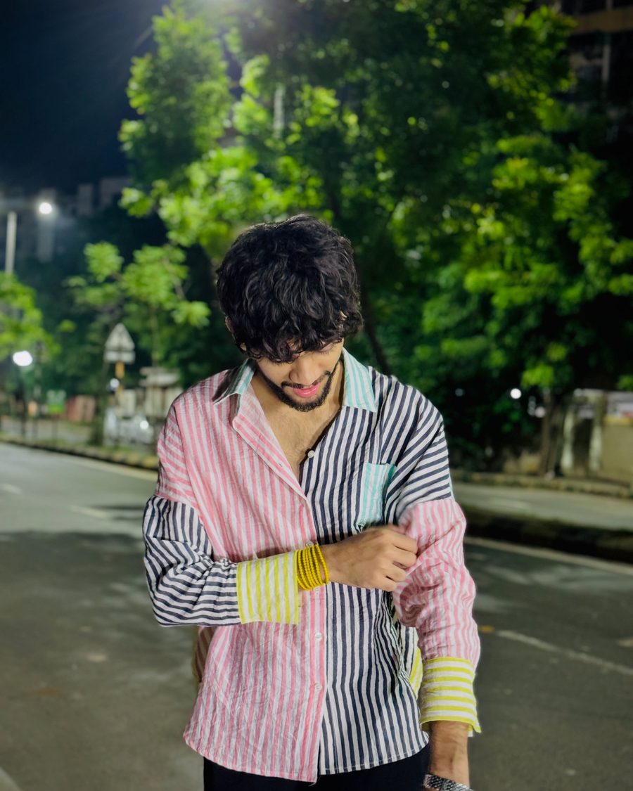 Devang Gohil looking down, adjusting his sleeve, on a street at night