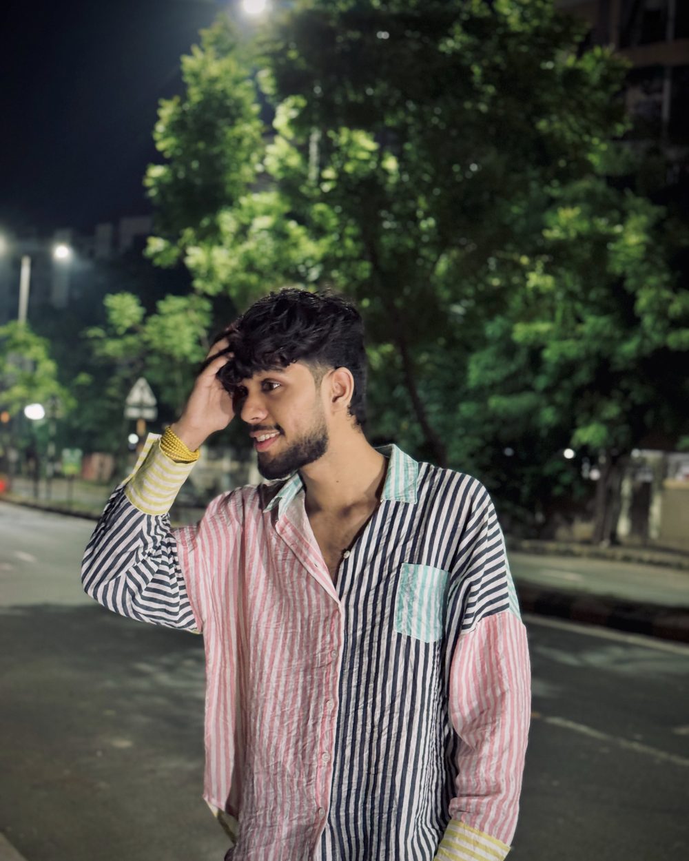 Devang Gohil on a tree-lined street at night, hand in his hair